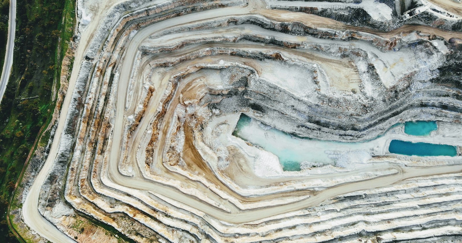 Open quarry with exposed rock benches and a blue water pool