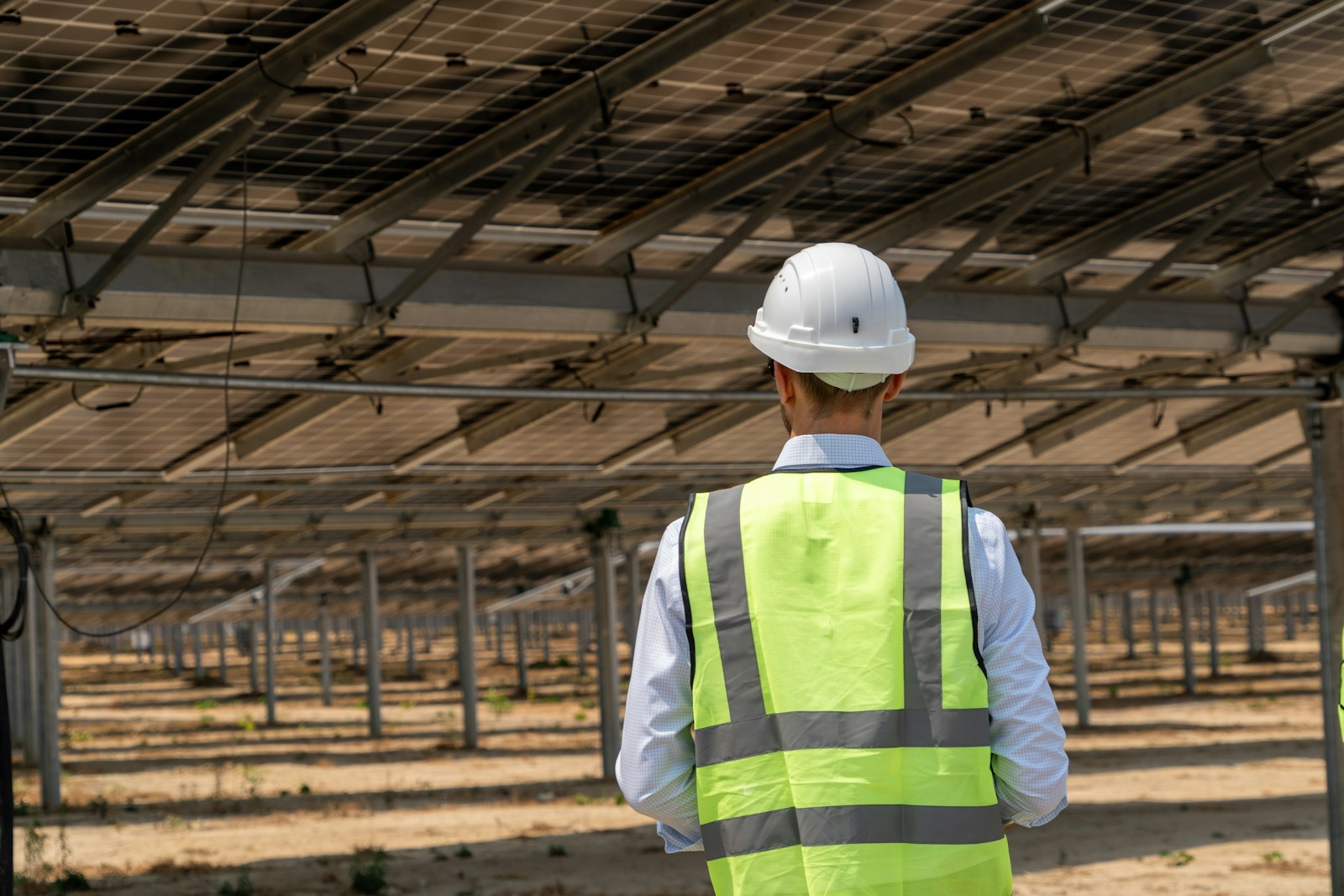 Engineer in a safety vest and hard hat inspecting a solar installation